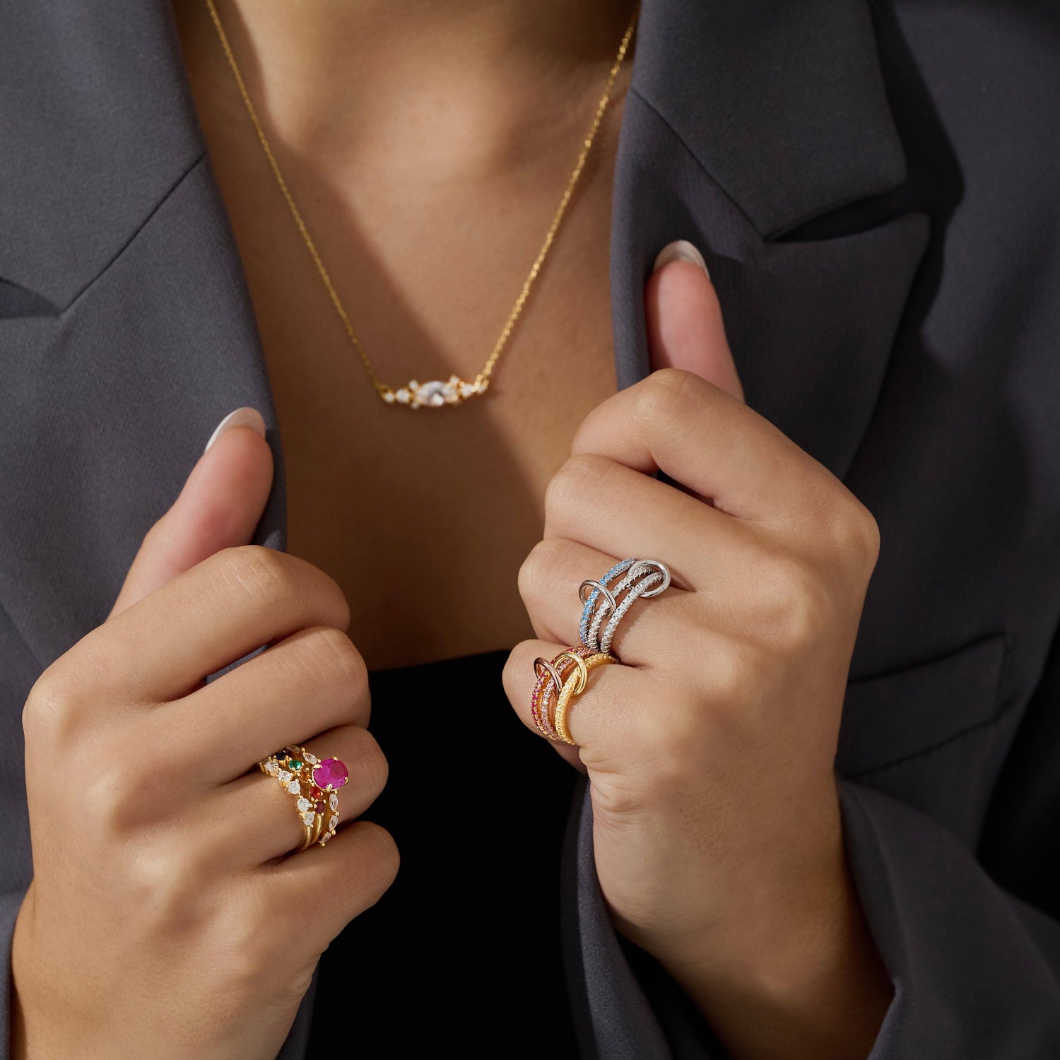 Woman wearing an 18K gold vermeil marquise necklace. Left hand with blue and pink 3 layer stacking rings. Right hand half eternity cubic zirconia, rainbow half eternity and pink pave ring.